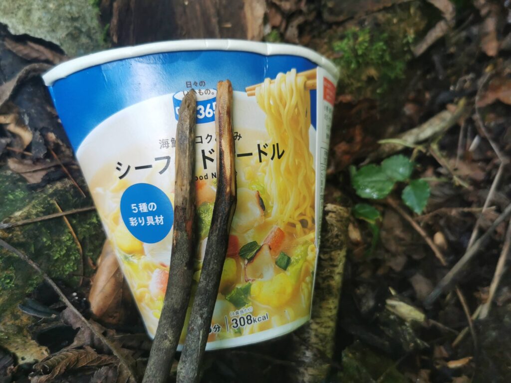 源流で枝を削って作った箸でカップラーメンを食べる様子